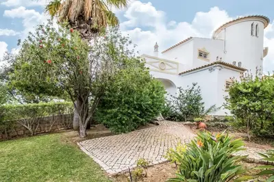 a white house with a palm tree and a garden at Falesia by Check-in Portugal in Albufeira