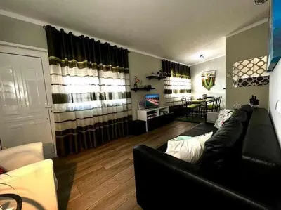 a living room with a black couch and a table at Green House by FHR estacionamento e WI-FI in Quarteira