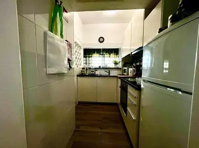 a small kitchen with a refrigerator and a sink at Green House by FHR estacionamento e WI-FI in Quarteira