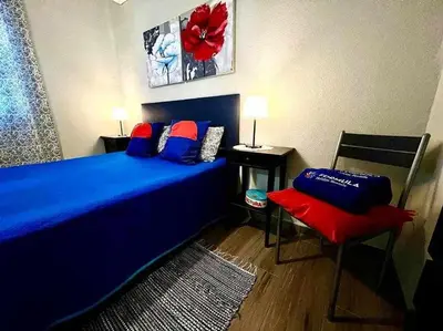 a bedroom with a blue bed and a red chair at Green House by FHR estacionamento e WI-FI in Quarteira