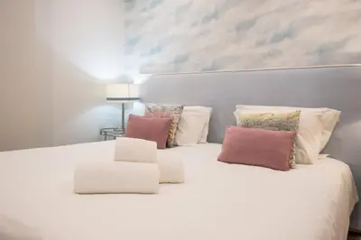 a white bed with three pillows on top of it at Al Marina View Uma - Lux apartment on the marina in Páteo