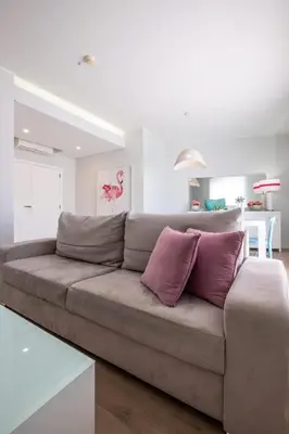 a couch with two purple pillows in a living room at Al Marina View Uma - Lux apartment on the marina in Páteo