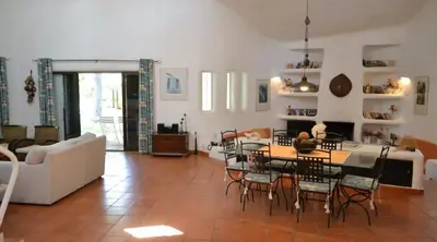 a living room with a couch and a table and chairs at Villa Pinhal- Beautiful Villa located in quiet area in Quarteira