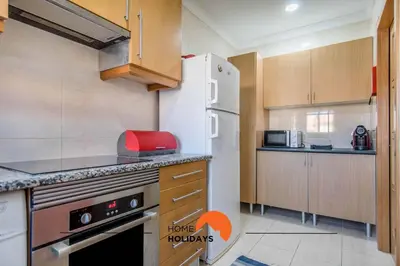 a kitchen with wooden cabinets and a white refrigerator at #123 T2 Pão das Areias by Home Holidays in Albufeira