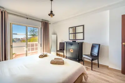 a bedroom with a bed and a chair and a window at AlgarSun - idealy situated holiday apartment with all modern comfort in Albufeira