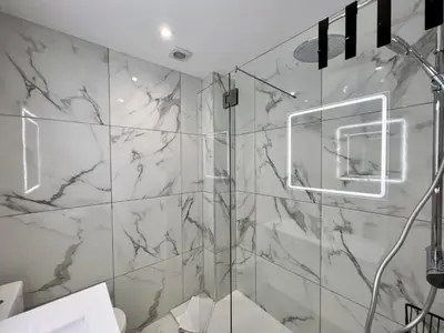 a bathroom with a shower with marble walls at Faro Deluxe by Homing in Faro