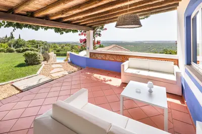 a patio with white couches and a table at Shantivillas Malhão in Azinhal