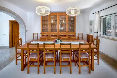 a dining room with a wooden table and chairs at Shantivillas Malhão in Azinhal