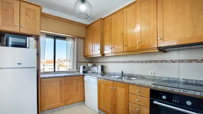 a kitchen with wooden cabinets and a white refrigerator at Sun-kissed Oasis W/ Pool by LovelyStay in Albufeira