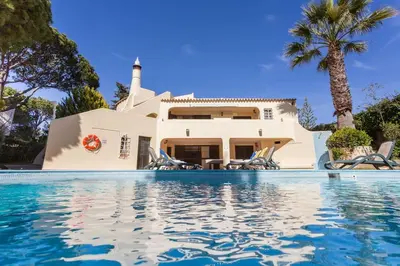 a villa with a swimming pool in front of a house at Villa Amarela in Vilamoura