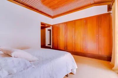 a bedroom with a white bed and wooden cabinets at Vila Alice in Quarteira