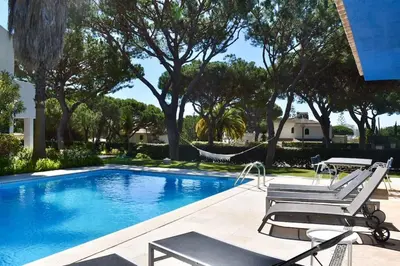 a swimming pool with two lounge chairs and a hammock at Vila Alice in Quarteira