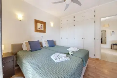 a bedroom with a green bed with a teddy bear on it at House Amendoeiras in Vilamoura