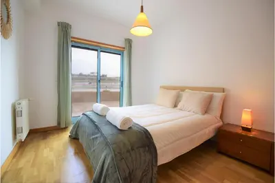 a bedroom with a bed and a large window at Marina de Albufeira T2 até 6 pax Com Piscina e Vista Marina in Albufeira