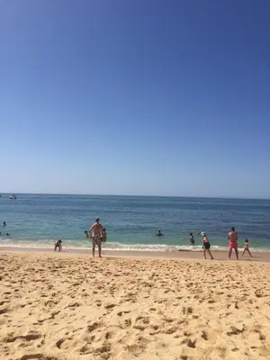 a group of people walking on the beach at Marina de Albufeira T2 até 6 pax Com Piscina e Vista Marina in Albufeira