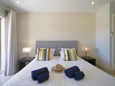 a bed with two blue pillows and a hat on it at Apartment Pine Hills Turquesa by Interhome in Vilamoura