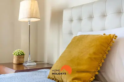 a yellow pillow on a bed with a lamp at #032 T2 Idalia by Home Holidays in Albufeira