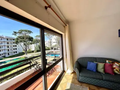 a living room with a couch and a large window at Vilamoura Palm Tree With Pool by Homing in Vilamoura