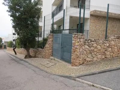 a stone wall with a blue gate in front of a building at Apartamento - CERRO MAR in Albufeira