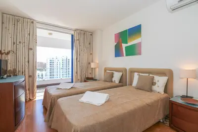 a hotel room with two beds and a large window at Apartamento Valerie in Vilamoura