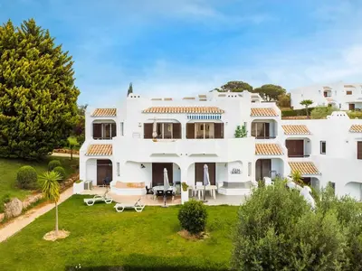 a boat in the water next to a cliff at Clube Albufeira: 2BR Prime Holidays Retreat in Albufeira