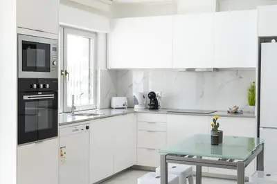 a white kitchen with a table and a microwave at Miral Beachside 5 - by HD Properties in Albufeira