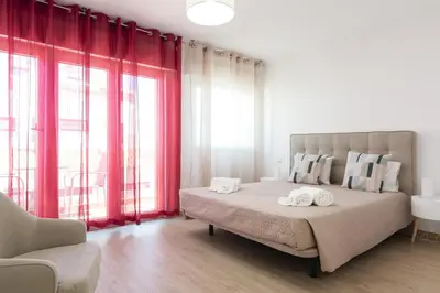 a bedroom with a large bed with red curtains at Miral Beachside 5 - by HD Properties in Albufeira