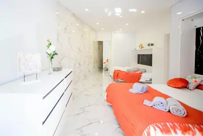 two beds in a white room with orange sheets at Dubai Apartment in Albufeira