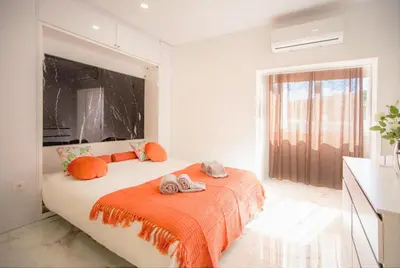 a bedroom with a bed with an orange blanket and a window at Dubai Apartment in Albufeira