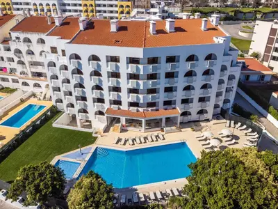a swimming pool with chaises and chairs next to a resort at Emeralds Albufeira by DK Stays in Albufeira