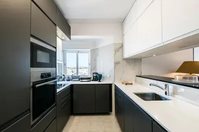 a kitchen with black and white cabinets and a sink at MarGalé - Swimming Pool - Beach - BY BEDZY in Galé