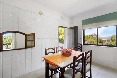 a dining room with a table and chairs and windows at Casa da Oliveira in Loulé