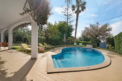 a swimming pool in a backyard with an archway at Casa da Oliveira in Loulé