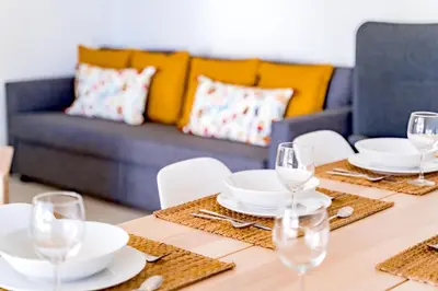 a small balcony with a wooden table and chairs at Melvin Jones St. 2bedroom apartment in Quarteira