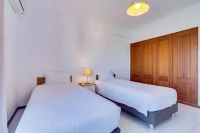 two beds in a room with white walls and wooden cabinets at Melvin Jones St. 2bedroom apartment in Quarteira