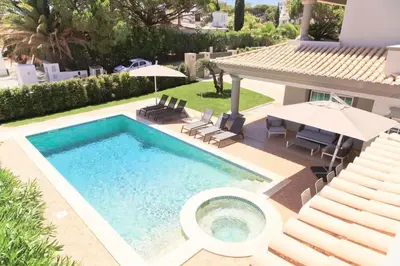 a pool with a table and chairs and a house at Villa Selena - Beautiful Luxury villa with massage baths in Quinta do Lago