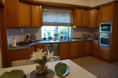 a kitchen with wooden cabinets and a table with flowers at Villa Selena - Beautiful Luxury villa with massage baths in Quinta do Lago