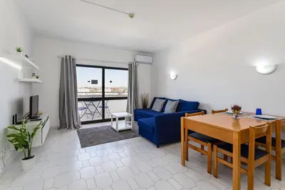 a white bed with two pillows and a blue headboard at The Albufeira Concierge - Pool & Sunset Balconies in Albufeira