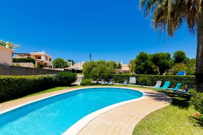 a swimming pool in a yard with chairs and a palm tree at Small Villa 4Pax -Shared Pool @ Homesbyfc in Albufeira