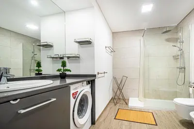 a bathroom with a sink and a washing machine at BeGuest Aveiros Beach View Apartment in Albufeira