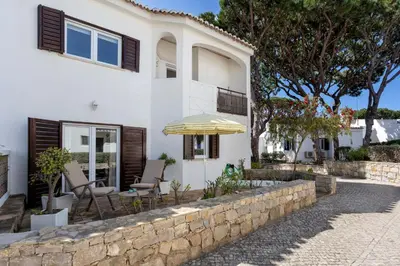 a white house with a stone wall and an umbrella at Villa Isabel in Vale do Lobo