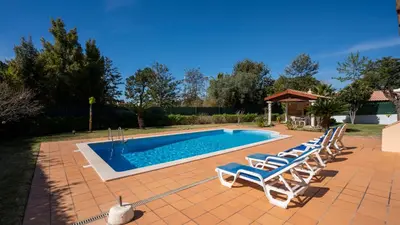 a group of lounge chairs next to a swimming pool at Amora Classic Villa in Vilamoura