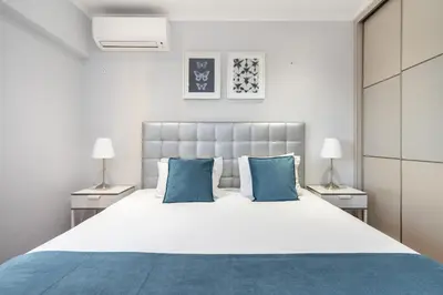 a bedroom with a large white bed with blue pillows at Amendoeiras Family Apartment in Quarteira