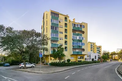 a yellow building on the side of a street at Amendoeiras Family Apartment in Quarteira