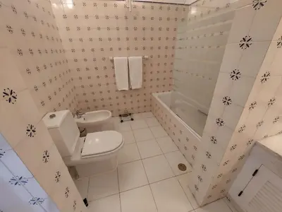 a white bathroom with a toilet and a sink at Ancão Beach Apartment in Almancil