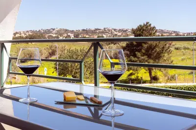 two glasses of wine sitting on a table on a balcony at Magnífico apartamento perto da praia in Albufeira