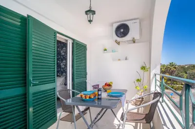 a table and chairs on a balcony with green shutters at Magnífico apartamento perto da praia in Albufeira