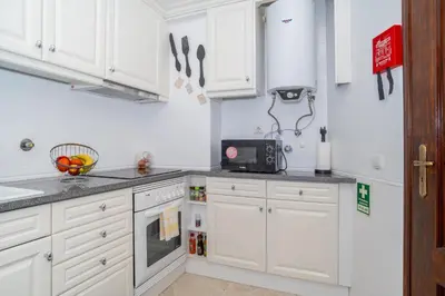 a white kitchen with white cabinets and a microwave at Magnífico apartamento perto da praia in Albufeira