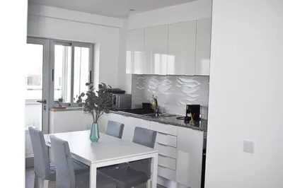 a white kitchen with a white table and chairs at GrowIN Stay Downtown in Faro
