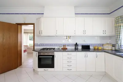 a kitchen with white cabinets and a stove top oven at Villa White Cottage by SAPvillas in Vilamoura